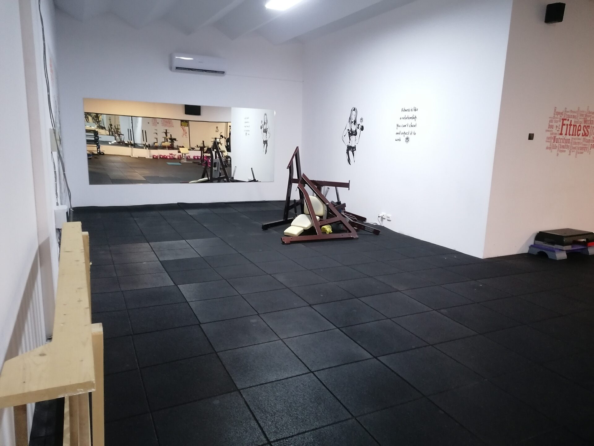 Sala de clase de la etaj, liberă: podea de cauciuc, perete alb cu oglindă și aer condiționat, pregătită pentru antrenamente de grup.